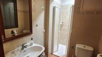 Un baño con lavamanos, inodoro y zona de ducha.