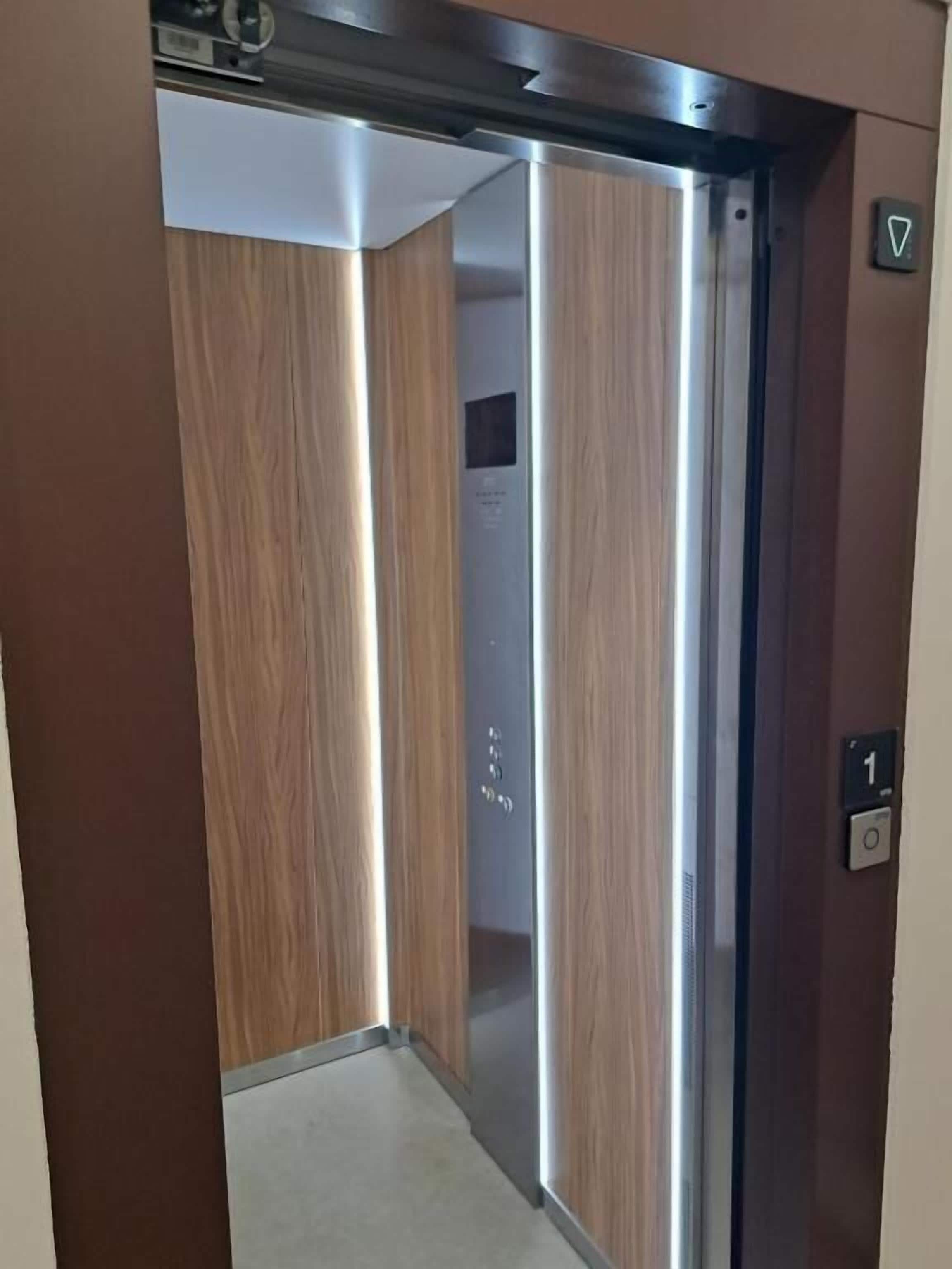 An elevator with a wooden finish and a control panel with a button marked '1'.