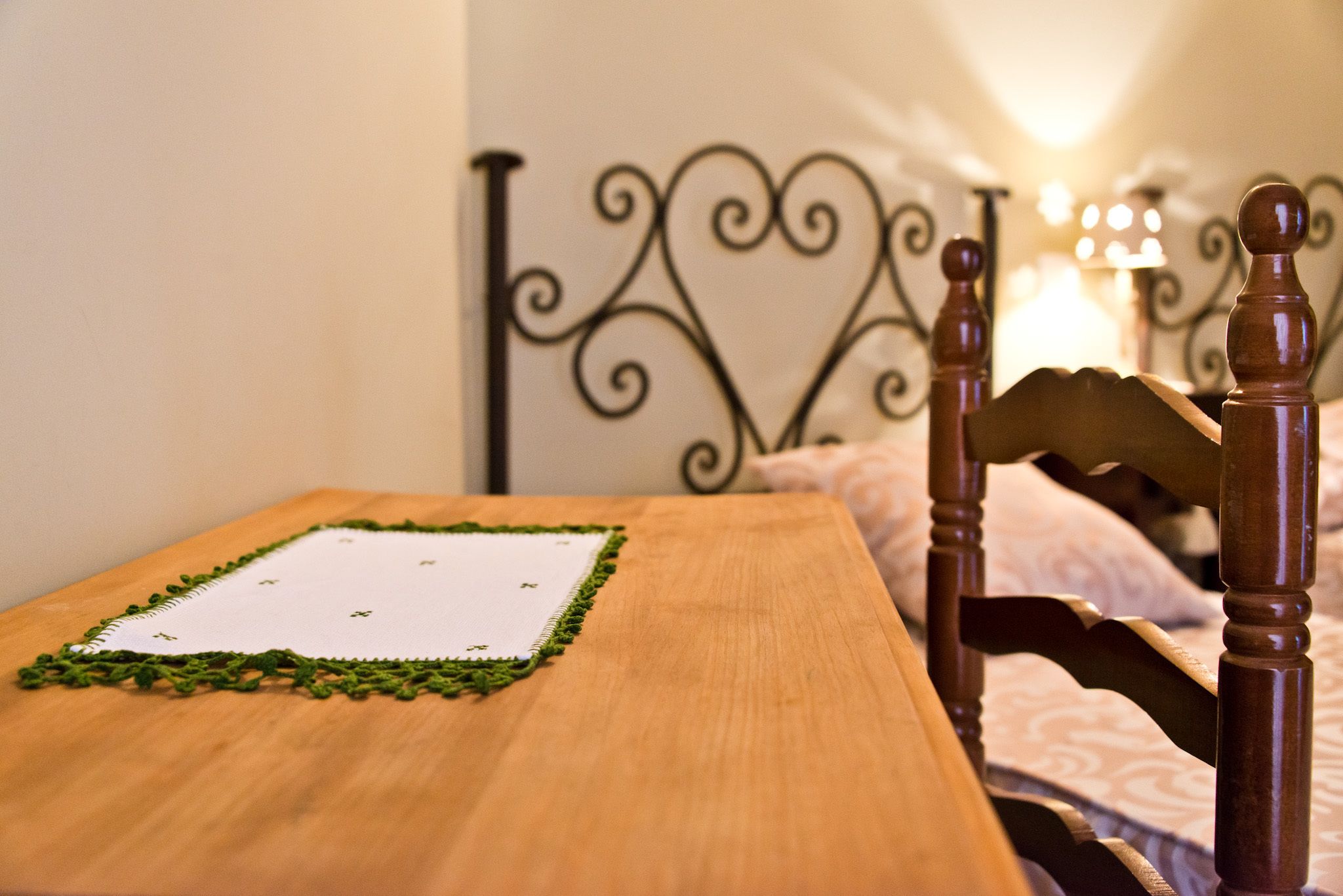 A wooden table with a green lace table runner and a white notepad.