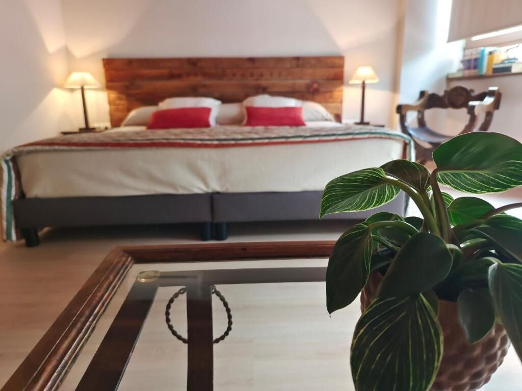Une chambre à coucher avec une tête de lit en bois, un lit avec des oreillers rouges et blancs, et une table de chevet avec une lampe.