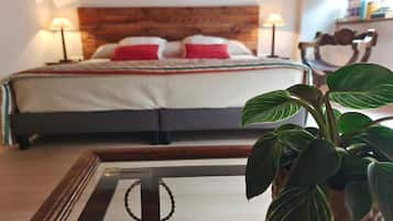 A bedroom with a wooden headboard, a bed with red and white pillows, and a bedside table with a lamp.