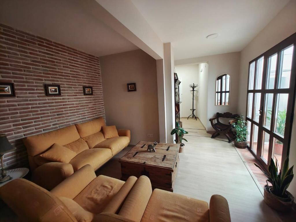 A living room with a brick wall, a sofa, a coffee table, and a view through large windows.