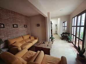 Una sala de estar con pared de ladrillo, un sofá, una mesa de centro y vistas amplias a través de grandes ventanales.
