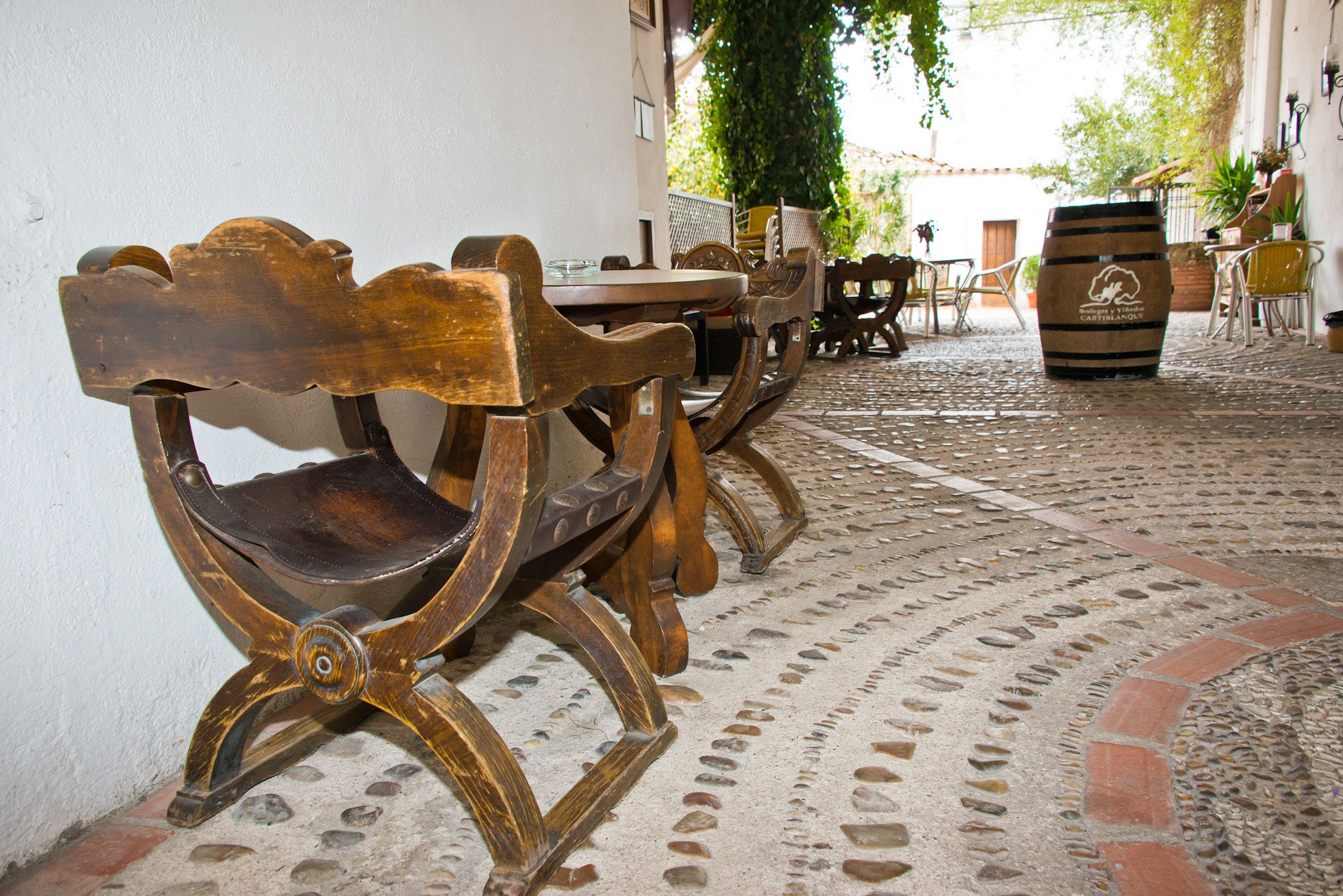 Un patio empedrado con muebles de madera rústica y un barril.