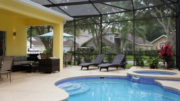 An indoor pool area with lounge chairs, a hot tub, and a covered seating area with a grill. - Shepherds Delight Apartment 5 Bedroom (Haines City)