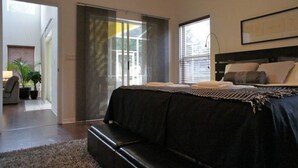 A bedroom with a bed, a bench, a window, and a door leading to a balcony. - Shepherds Delight Apartment 5 Bedroom (Haines City)