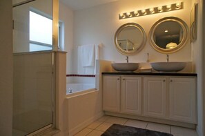A bathroom with a bathtub, two sinks, and a vanity with cabinets.