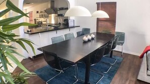 A modern dining area with a dark wooden table, six chairs, and a blue rug. - Shepherds Delight Apartment 5 Bedroom (Haines City)
