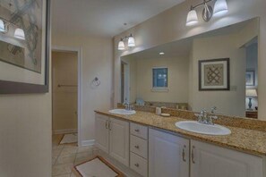 A bathroom with two sinks, a large mirror, and a door leading to another room. - Club at Mexico Beach 2D Apartment 2 Bedroom (Port St. Joe)