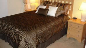 A neatly made bed with patterned bedding, a wooden headboard, and bedside tables with lamps. - Brooks Retreat Apartment 4 Bedroom (Haines City)