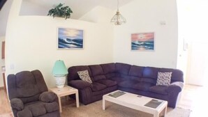 Ein Wohnzimmer mit Ecksofa, einem kleinen Beistelltisch und einem Couchtisch.