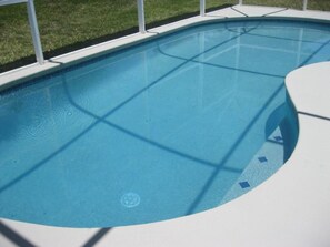 A clear blue swimming pool with a white deck and a grassy area in the background. - Waterview 1685 Apartment 4 Bedroom (Haines City)