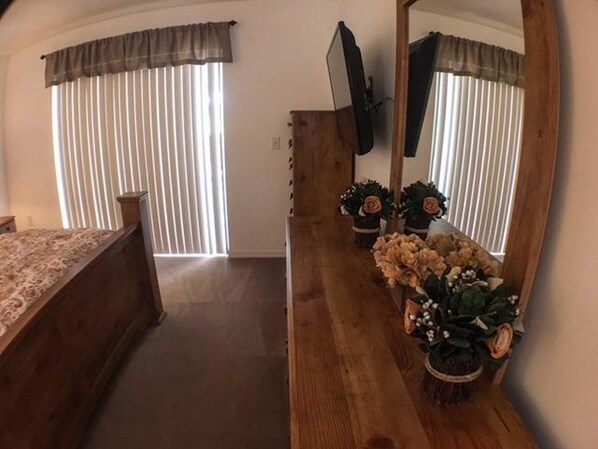 Un dormitorio con una cama, un aparador de madera, un espejo y una planta en maceta.