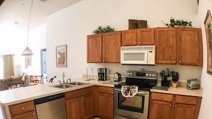A compact kitchen with wooden cabinets, a microwave, a stove, and a dishwasher.