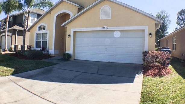 A residential house with a garage, a driveway, and a well-maintained lawn.