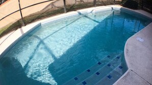 Une piscine dont le bord est revêtu de carreaux et dont l’eau est d’un bleu limpide.
