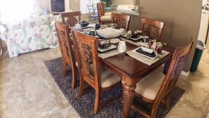 Un coin repas avec une table et des chaises en bois, un ventilateur de plafond et une fenêtre avec des stores.