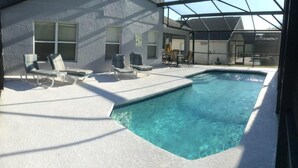 Ein Swimmingpool mit Liegestühlen und einer überdachten Terrasse.