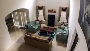 Ein Wohnzimmer mit einer Couch, einem Couchtisch und einem Kamin. Ein Fernseher und ein Gemälde hängen an der Wand.