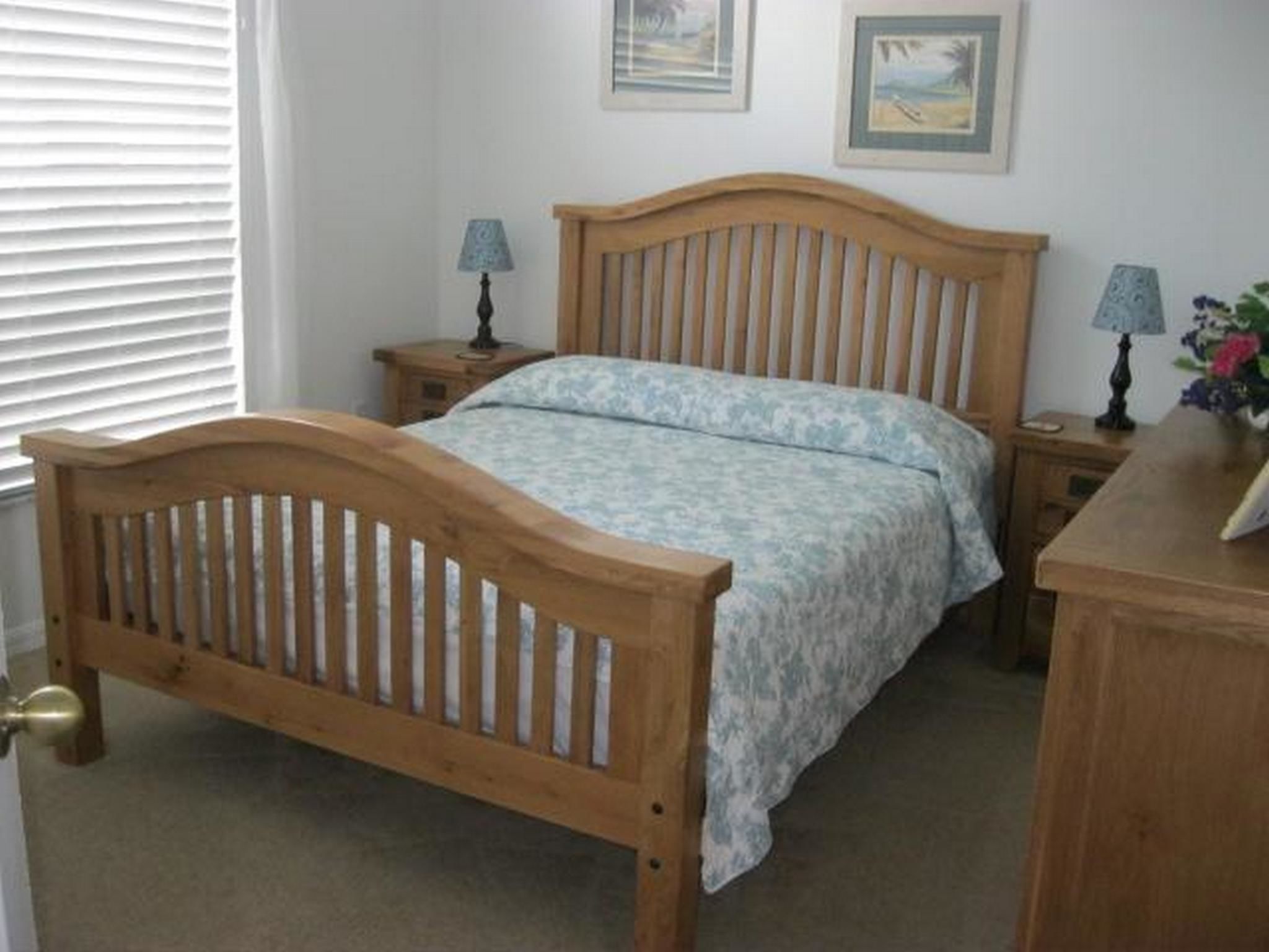 A bedroom with a wooden bed, two bedside tables, a nightstand, and a dresser.
