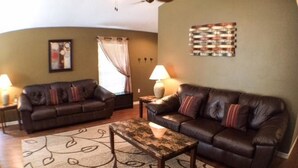 A living room with two leather sofas, a coffee table, and a patterned rug.