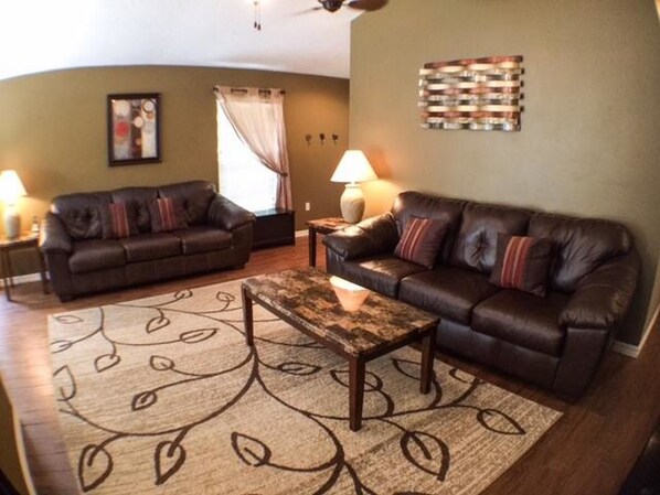A living room with two leather sofas, a coffee table, and a patterned rug.
