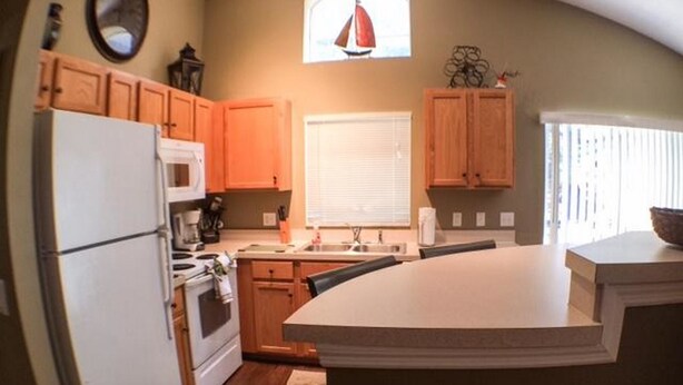 A kitchen with wooden cabinets, a white refrigerator, a stove, and a large island.