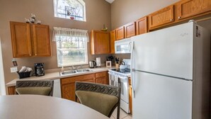 Una cocina compacta con armarios de madera, un refrigerador blanco y una zona de comedor con dos sillas.