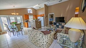 Un espacio habitable amplio con una mesa de comedor, dos sofás, un televisor y una cocina al fondo.