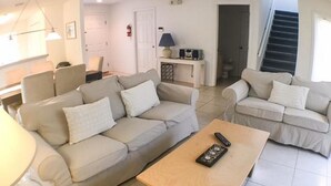 A living room with two beige sofas, a wooden coffee table, and a lamp.