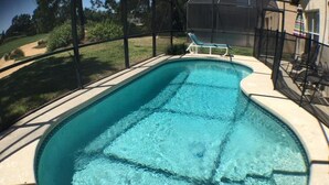 A clear swimming pool with a sunshade and lounge chairs. - Kokomo House Holiday home 3 Bedroom (Haines City)