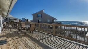Terraza de madera con mobiliario exterior con vista a la playa y al océano.