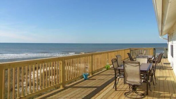 Una terraza de madera con mobiliario exterior con vistas al océano.