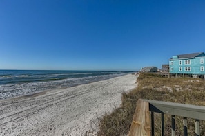 Ein Strand mit einer Holzpromenade, die zu einem blauen Gebäude führt.