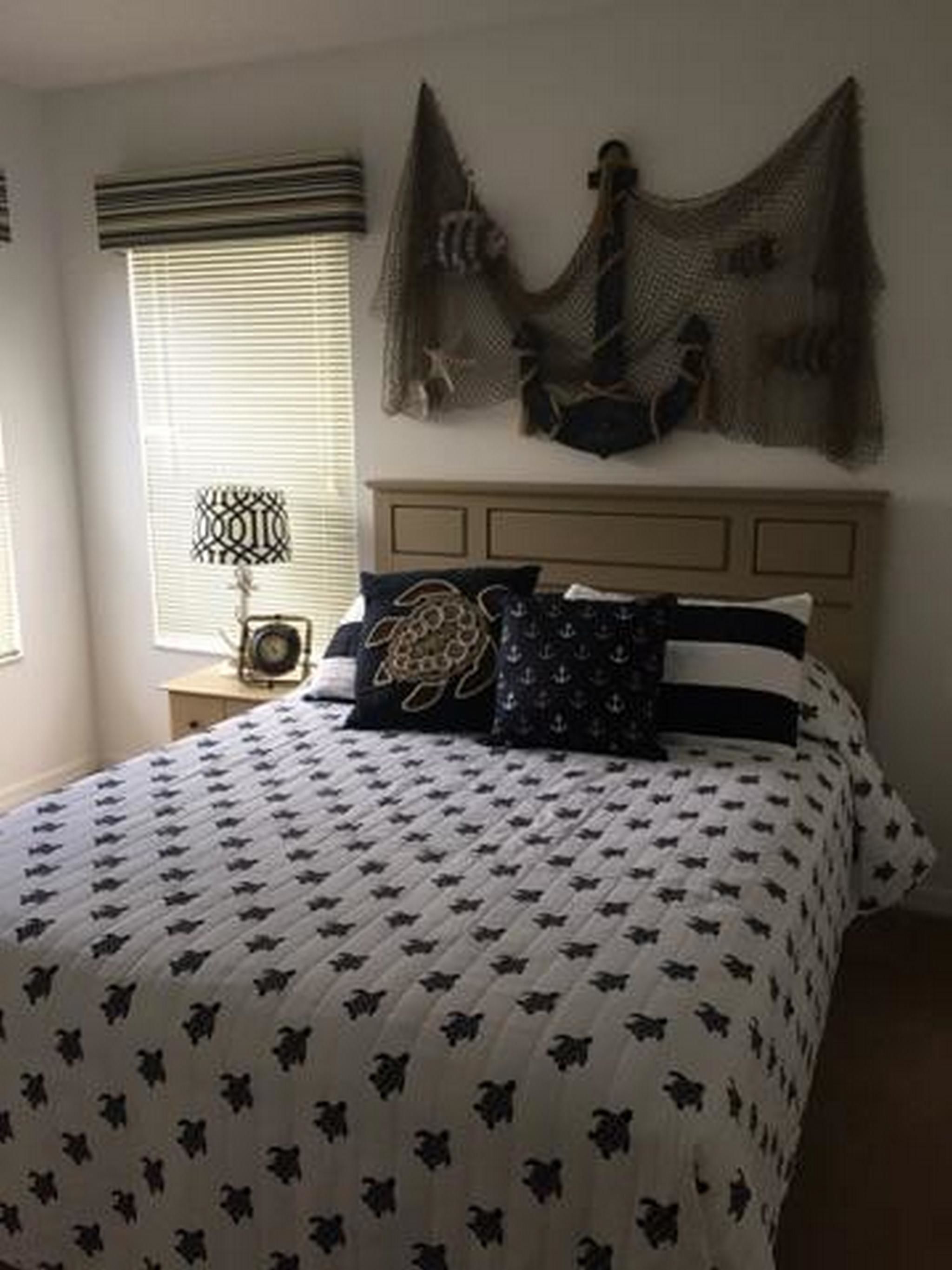 Een slaapkamer met een bed, nachtkastje, lamp en een decoratie aan de muur.