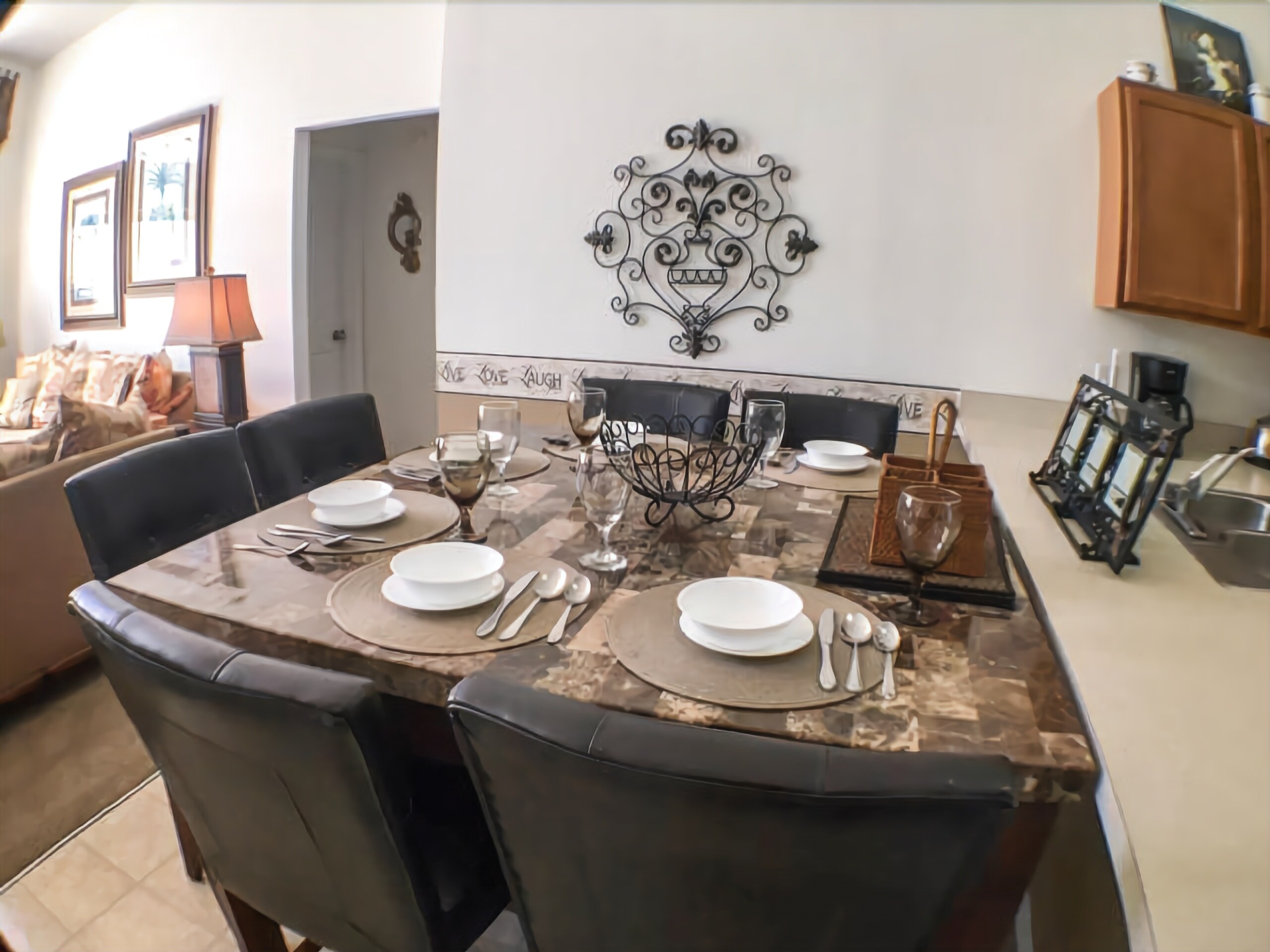 A dining area with a marble table set for four, surrounded by black chairs.