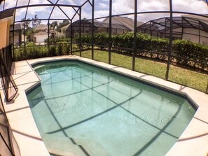Ein rechteckiger Pool mit einer gefliesten Kante, umgeben von einem Metallzaun und Glasscheiben.