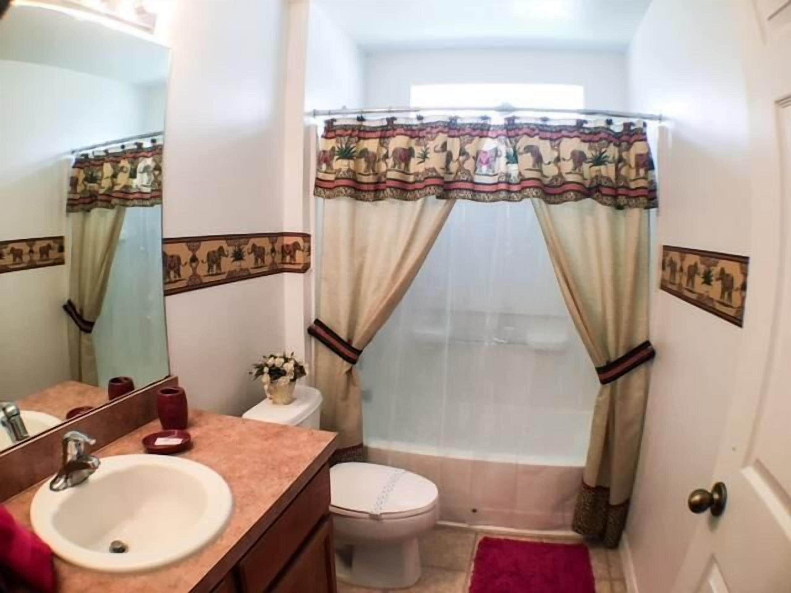 Un bagno con lavandino, WC e tenda per la doccia.