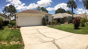 A residential neighborhood with houses, a driveway, and a clear sky.