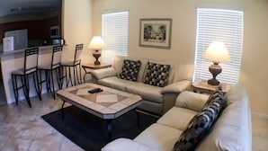A living room with a sofa, two armchairs, a coffee table, and a dining area with chairs and a table. - Mariner Pad Apartment 4 Bedroom (Haines City)