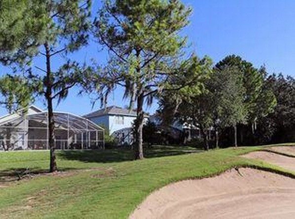 Un campo de golf con cielo despejado, un pabellón cubierto y un césped bien cuidado.