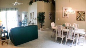 Un comedor con una mesa y sillas blancas, un ventilador de techo y una araña.