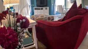 A living room with a red sofa, a white cabinet, and a television on the wall. - Park Place Retreat Apartment 4 Bedroom (Haines City)