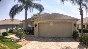 A residential driveway leading to a garage with a tiled walkway and palm trees. - Park Place Retreat Apartment 4 Bedroom (Haines City)