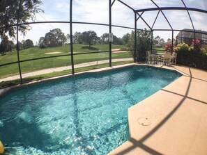 A clear swimming pool with a view of a golf course through a screened enclosure. - Park Place Retreat Apartment 4 Bedroom (Haines City)