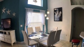 A dining area with a table, chairs, and a television in the corner. - Park Place Retreat Apartment 4 Bedroom (Haines City)