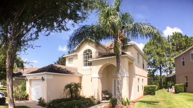 A single-story house with a garage, a covered patio, and a well-maintained lawn. - Hemingway Golf View Apartment 4 Bedroom (Haines City)