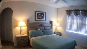 A bedroom with a bed, two bedside tables with lamps, a framed picture on the wall, and a window with curtains. - Calabay Dream Apartment 4 Bedroom (Haines City)