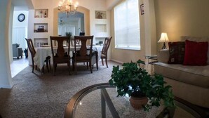 A dining area with a chandelier, a dining table with chairs, and a potted plant on a glass table. - Kokomo 2749 Apartment 6 Bedroom (Haines City)