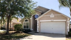 A residential house with a garage, a driveway, and a well-maintained lawn. - Kokomo Golf View Apartment 4 Bedroom (Haines City)